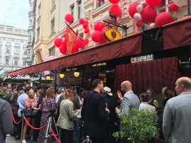 Viele 'schöne und berühmte' Leute vor dem Kameel, über dessen Markisen viele rote Campariballons schweben