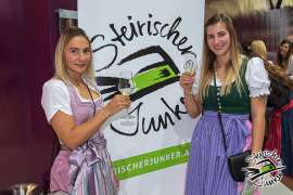 Zwei Damen in feschen Dirndln vor dem Junker Logo