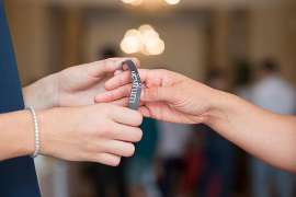 Zwei Hände streifen einer dritten Hand das Eintritts-Gumiband über
