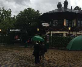 Einige Leute mit Grünen Regenschirmen gehen auf den Eingang des Schweizerhaus zu