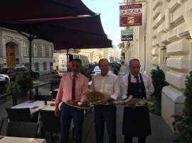 Lotfi Nasr (Inhaber), Peter Dobcak (WKO Gastronomie-Obmann) und Antonio (Kellner der Trattoria) servieren Speisen im Aussenbereich
