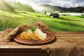 Woerle Emmentaler und Mondseer, im Bild auf einem Teller, im Hintergrund die Alpen, kann man ab sofort auch in Scheiben genießen.