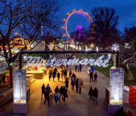 Blick auf den nächtlichen Wintermarkt, im Hintergrund das beleuchtete Riesenrad