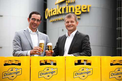 Tobias Frank und Matthias Ortner stossen hinter einer halbhohen Wand aus Ottakringer Kisten mit Bier an