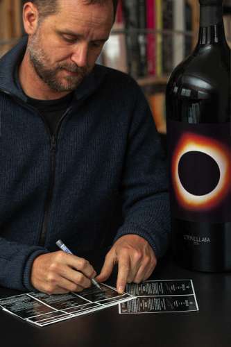 Tomas Saraceno signiert Ornellaia Etiketten, im VOrdergrund eine Großflasche im von ihm entworfenen Design