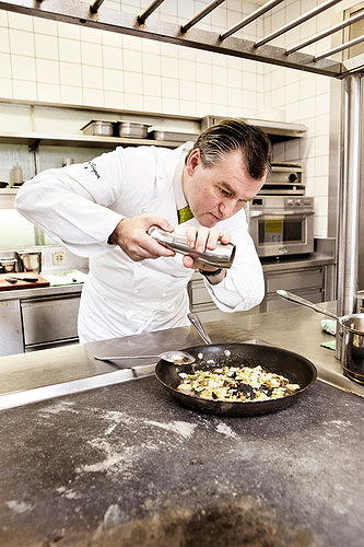 Toni Mörwald in der Küche, mit der Pfeffermühle über einer Casserolle