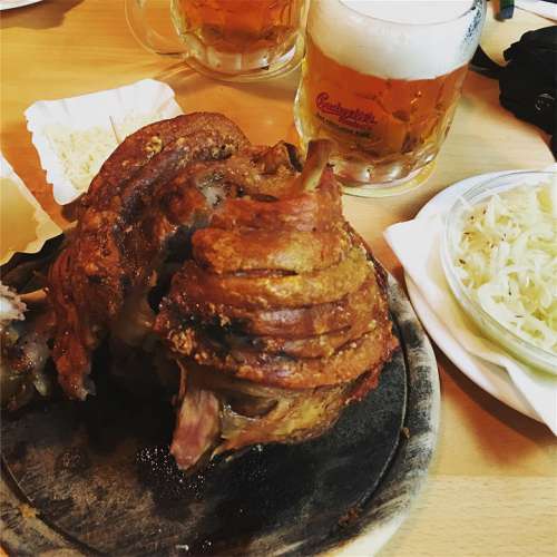 Eine knusprige Stelze imm Schweizerhaus, daneben Krautsalat im Extraschüsserl, dahinter Budweiser