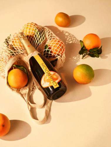 Eine Flasche Chandon Garden Spritz zwischen ganzen Orangen