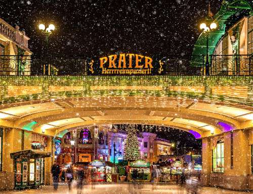 Blick auf das strahlend erleuchtete Eingangstor mit Aufschrift 'Prater Wintermarkt - Herrreinspaziert!'