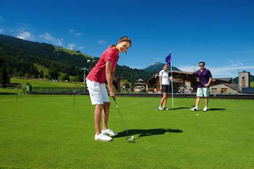 Frau beim Golfen am Putting Green im Sommer