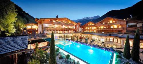 Das Hotel Quelle bei Nacht mit beleuchtetem Pool, im Hintergrund die Berge