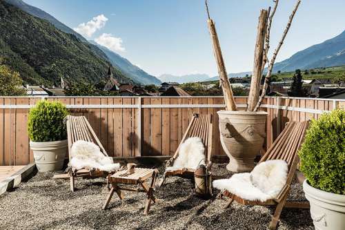 Panoramaterrasse im Sommer mit Liegestühlen, dahinter die Hochalpen