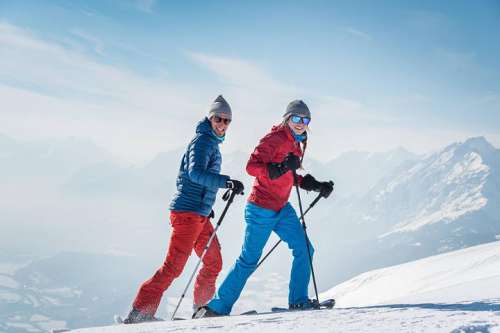 Pärchen beim Schneeschuhwandern vor verschneiter Bergkulisse