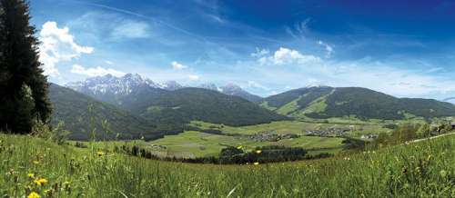 Olang: Panoramablick im Sommer mit Wäldern und schroffen Bergspitzen