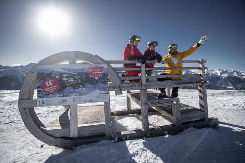 Skifahrer auf großem Schlitten vor herrlich winterlicher Bergkulisse
