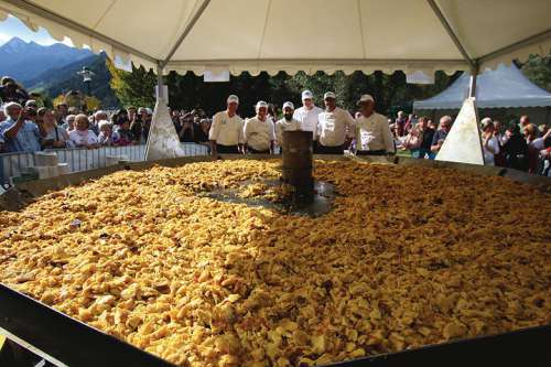 Leute stehen um eine riesige Pfanne Kaiserschmarrn