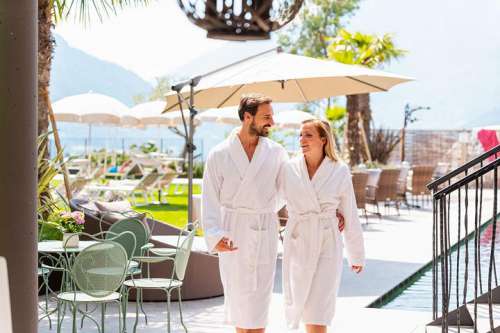 Wellness-Auszeit zu zweit: Ein Päärchen im Bademantel auf der Poolterrasse im Weinmesser